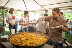 Persona cuinant una paella a l'aire lliure en una celebració del Casal Català de Graz